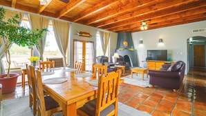 A wooden dining area with a table and chairs, a sofa, and a television.