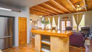 A spacious kitchen with a wooden ceiling and a central island, a refrigerator, and a dining area with chairs.