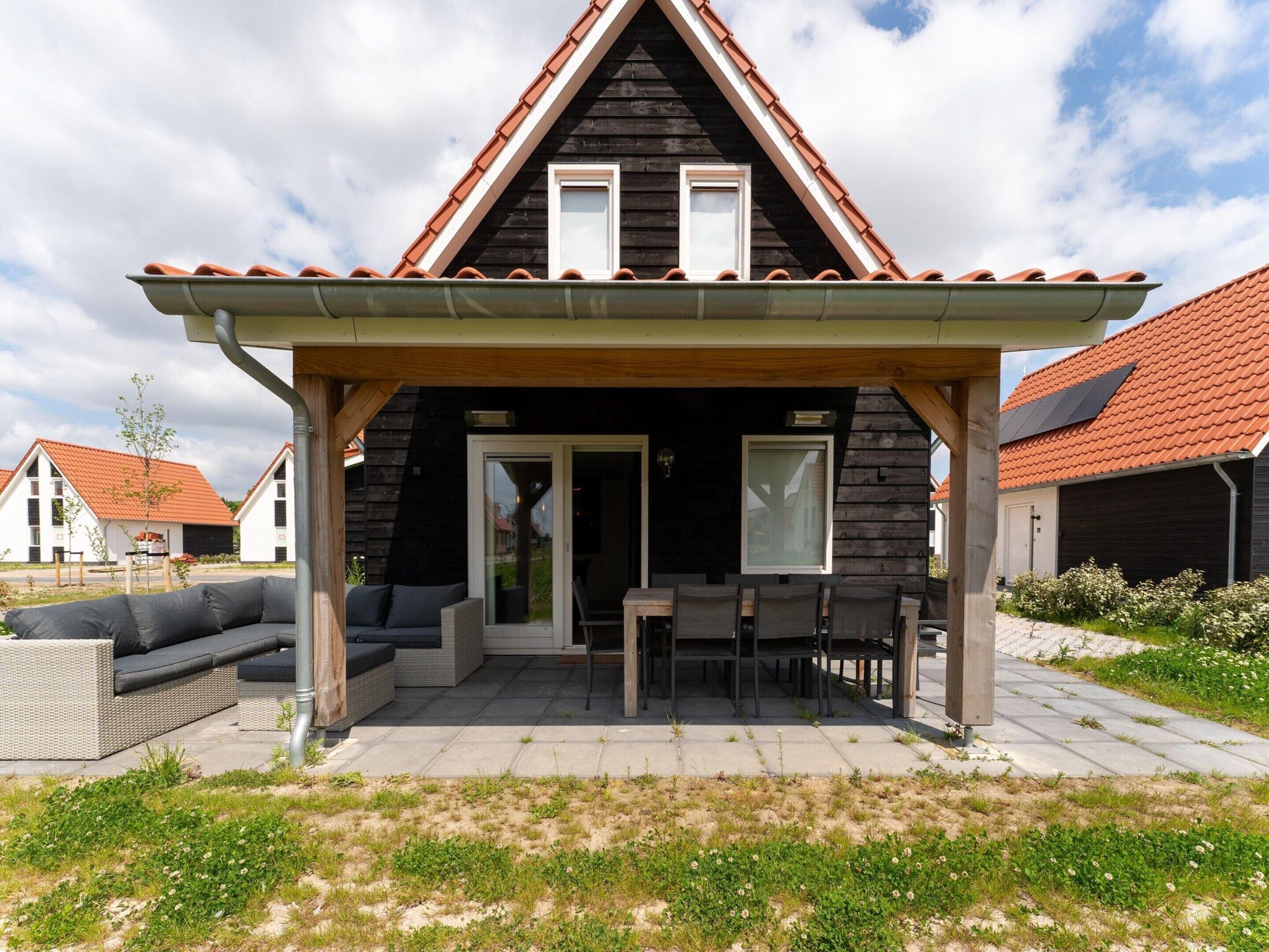 A wooden house with a pitched roof and a covered patio area.