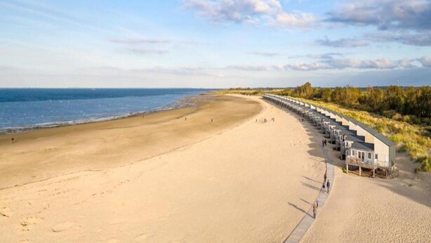 En strand med en række strandhuse langs kysten.