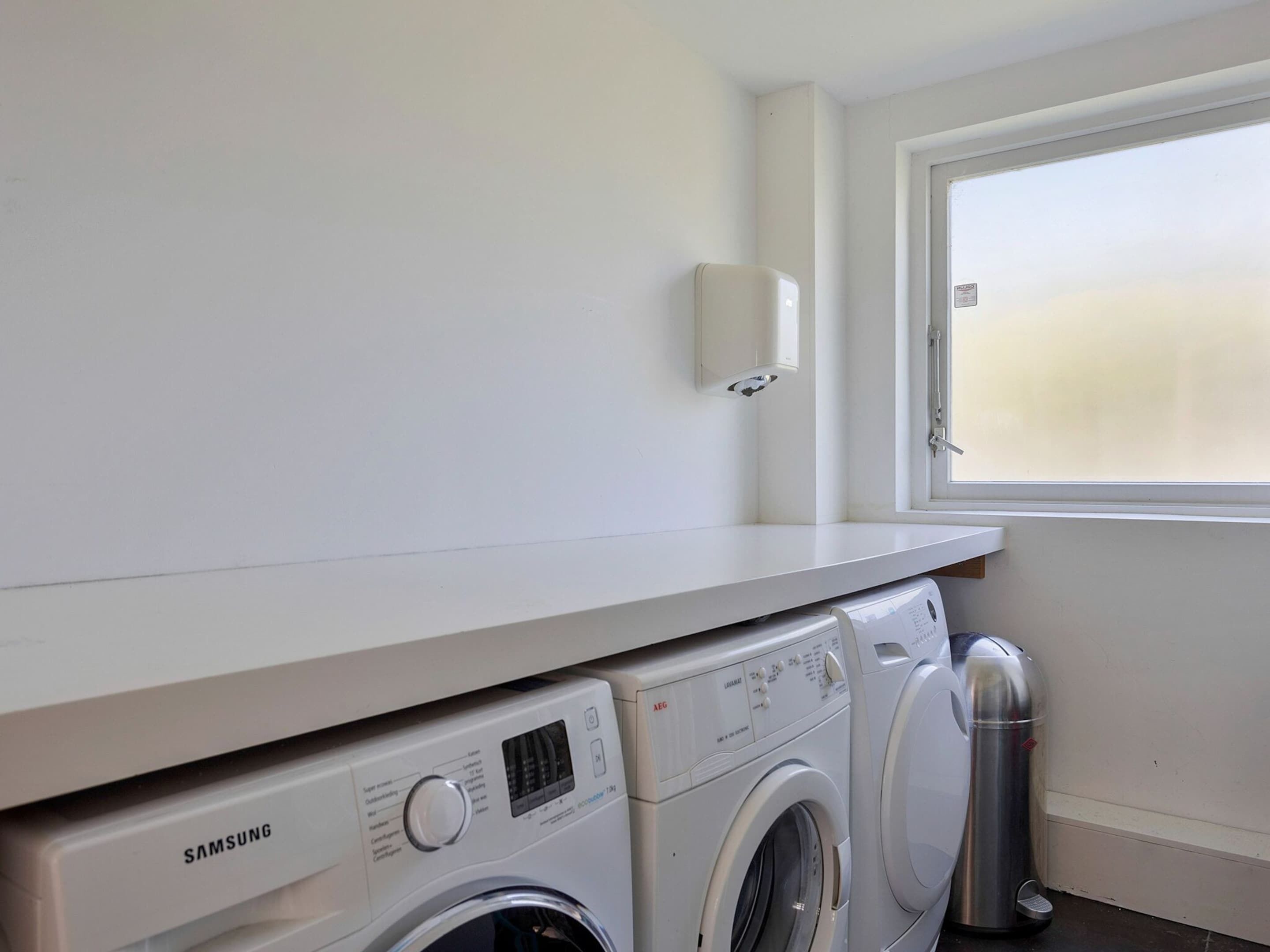 A laundry area with a Samsung washing machine, a dryer, and a stainless steel water heater.