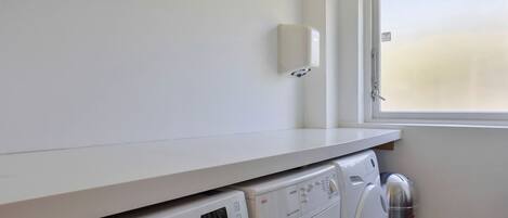 A laundry area with a Samsung washing machine, a dryer, and a stainless steel water heater.