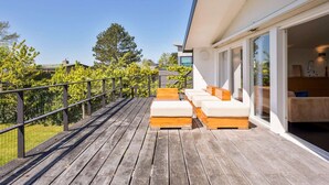 A wooden deck with outdoor seating and a glass door leading to a modern interior. - Villa Sternlaan 24 Kamperland (Kamperland)