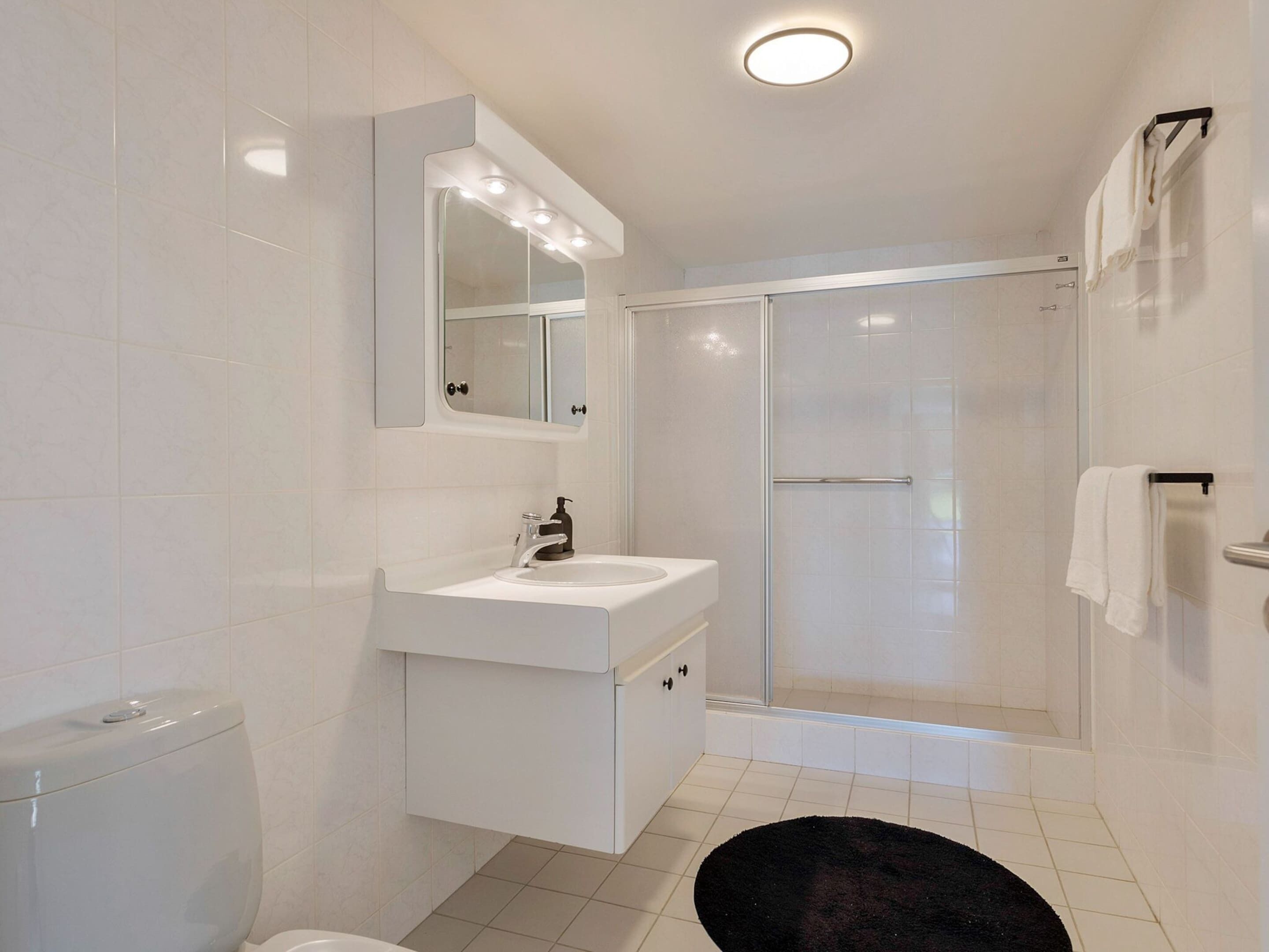 Une salle de bain moderne avec un lavabo blanc, un miroir et des toilettes.
