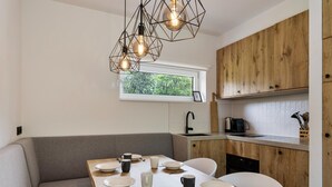 Een moderne keuken met houten kastjes, een eettafel gedekt met borden en kopjes, en een geometrische hanglamp.
