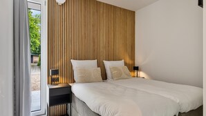 Een moderne slaapkamer met een groot bed, een wand van houten panelen en uitzicht op groen.