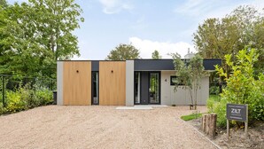 Een modern gebouw met een grindpad, houten panelen en een bord waarop vrije kamers staan aangegeven.