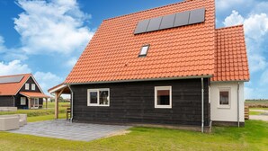 A modern house with a red-tiled roof, black exterior walls, and a small window. - Beach Bliss Romantic Retreat (Scherpenisse)
