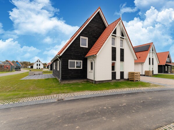 A row of modern houses with red-tiled roofs and a paved driveway. - Beach Bliss Romantic Retreat (Scherpenisse)