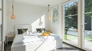 A modern bedroom with a large bed, two bedside tables, and a view of the outdoors through a sliding glass door. - Holiday Home Near Veerse Meer (Kamperland)