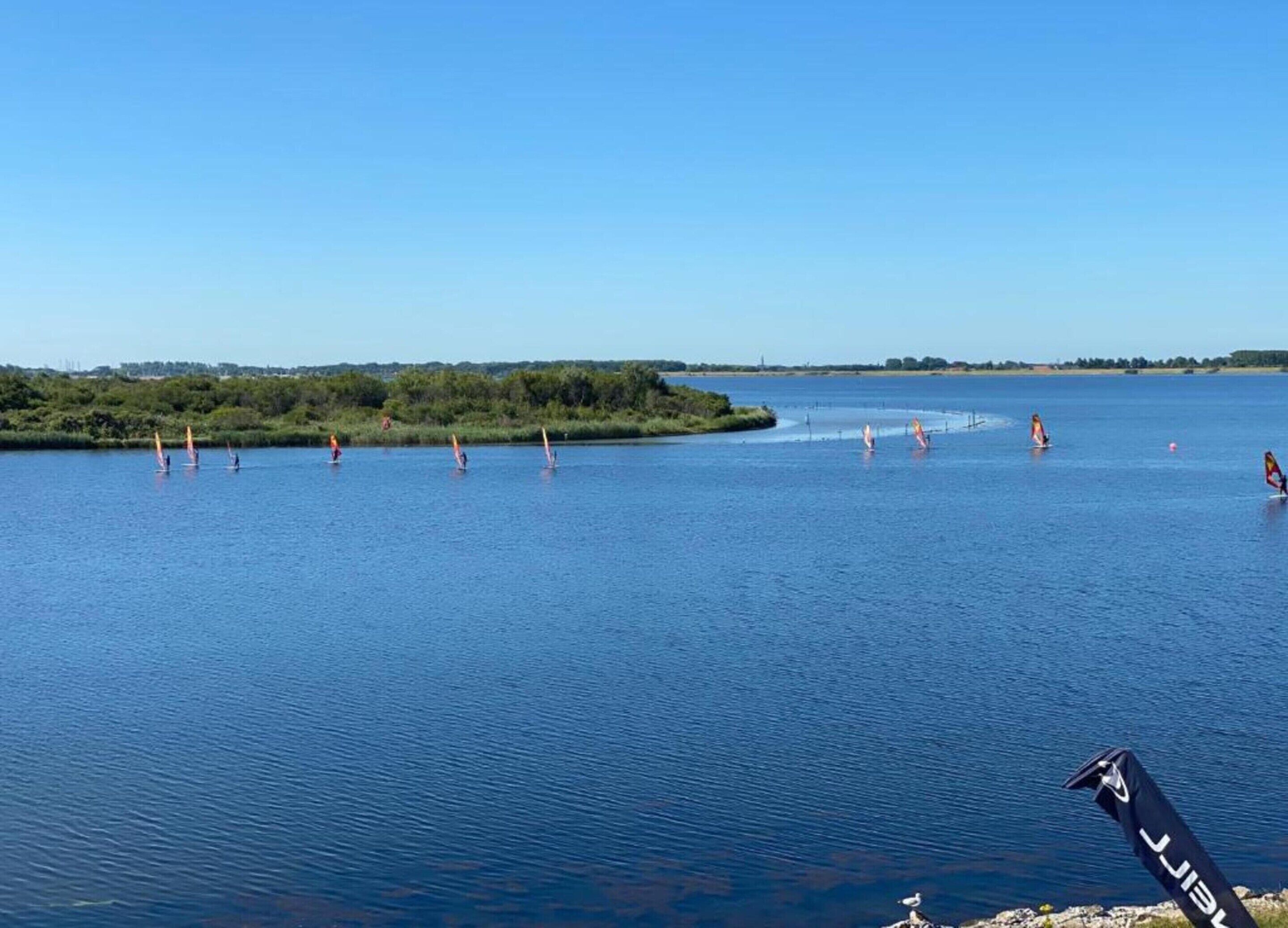 A calm lake with people windsurfing.