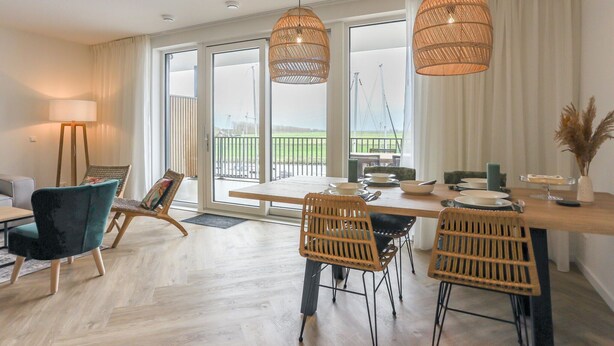A modern dining area with a wooden table, wicker chairs, and pendant lights. - Apartment Kamperland Near Veerse Meer (Kamperland)