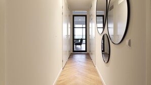 A hallway with a wooden floor and white walls, leading to a balcony with a view. - Apartment Kamperland Near Veerse Meer (Kamperland)