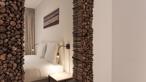 A modern hotel room with a unique rock-like mirror frame, a neatly made bed, a bedside table, and a painting on the wall. - Apartment Kamperland Near Veerse Meer (Kamperland)