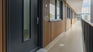 A corridor with wooden paneling and black-framed windows, leading to a building entrance. - Apartment Kamperland Near Veerse Meer (Kamperland)