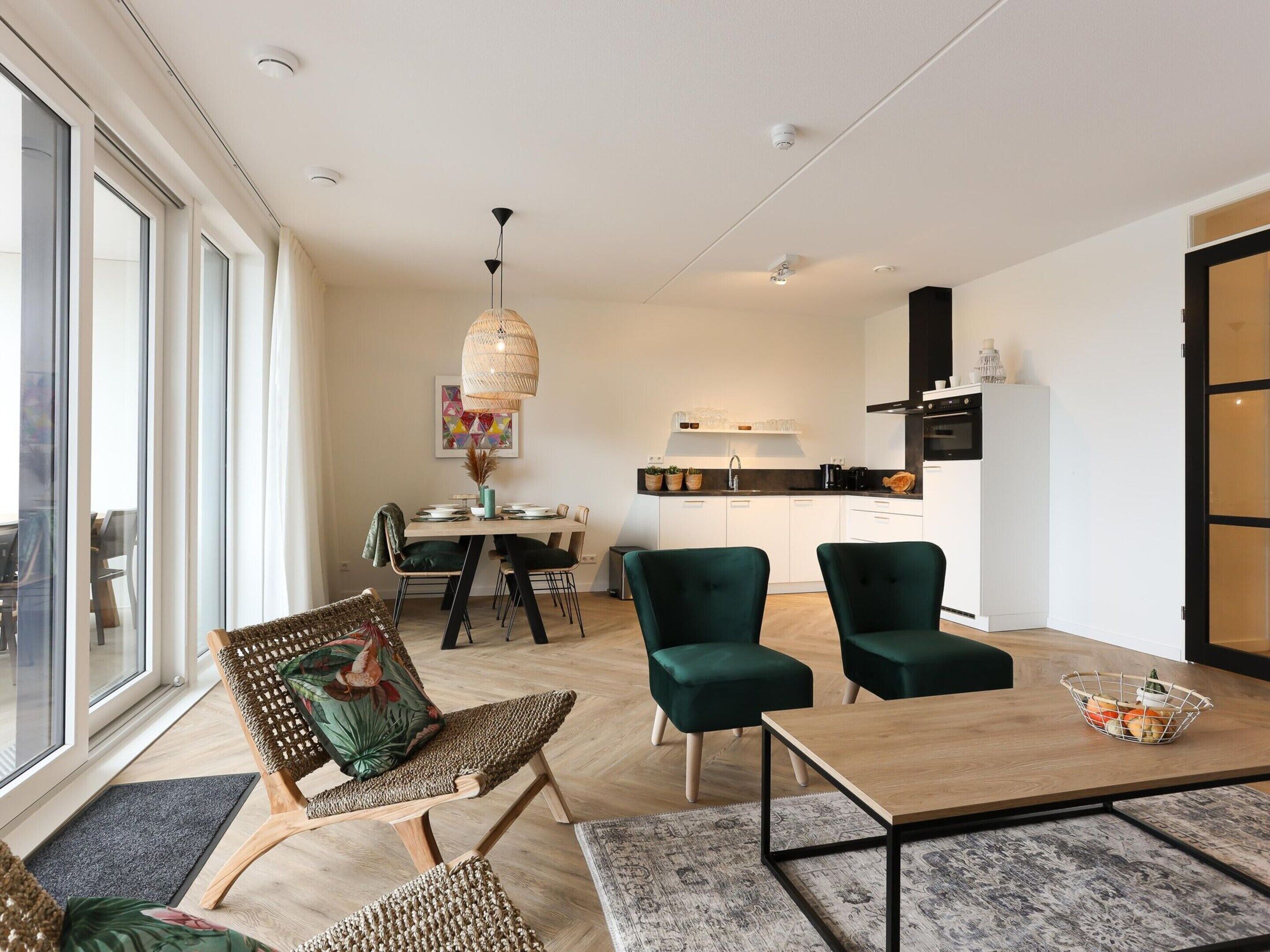 A modern living room with a dining area, a kitchen, and large windows.