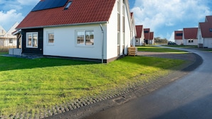 Un immeuble résidentiel avec un toit rouge, des murs blancs et des panneaux solaires.