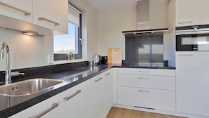 A modern kitchen with white cabinets, a stainless steel sink, and a black countertop.