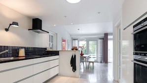 Une cuisine moderne avec un poêle noir, des armoires blanches et un coin repas comprenant une table et des chaises.