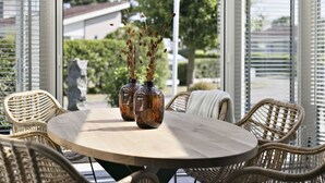 A round table with wicker chairs and two glass vases with dried plants.