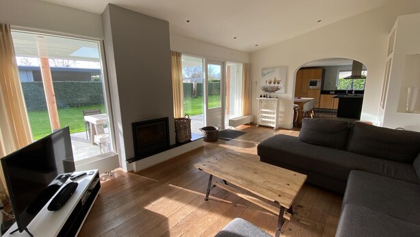 Een ruime woonkamer met een groot raam, een open haard, een bank en een televisie.