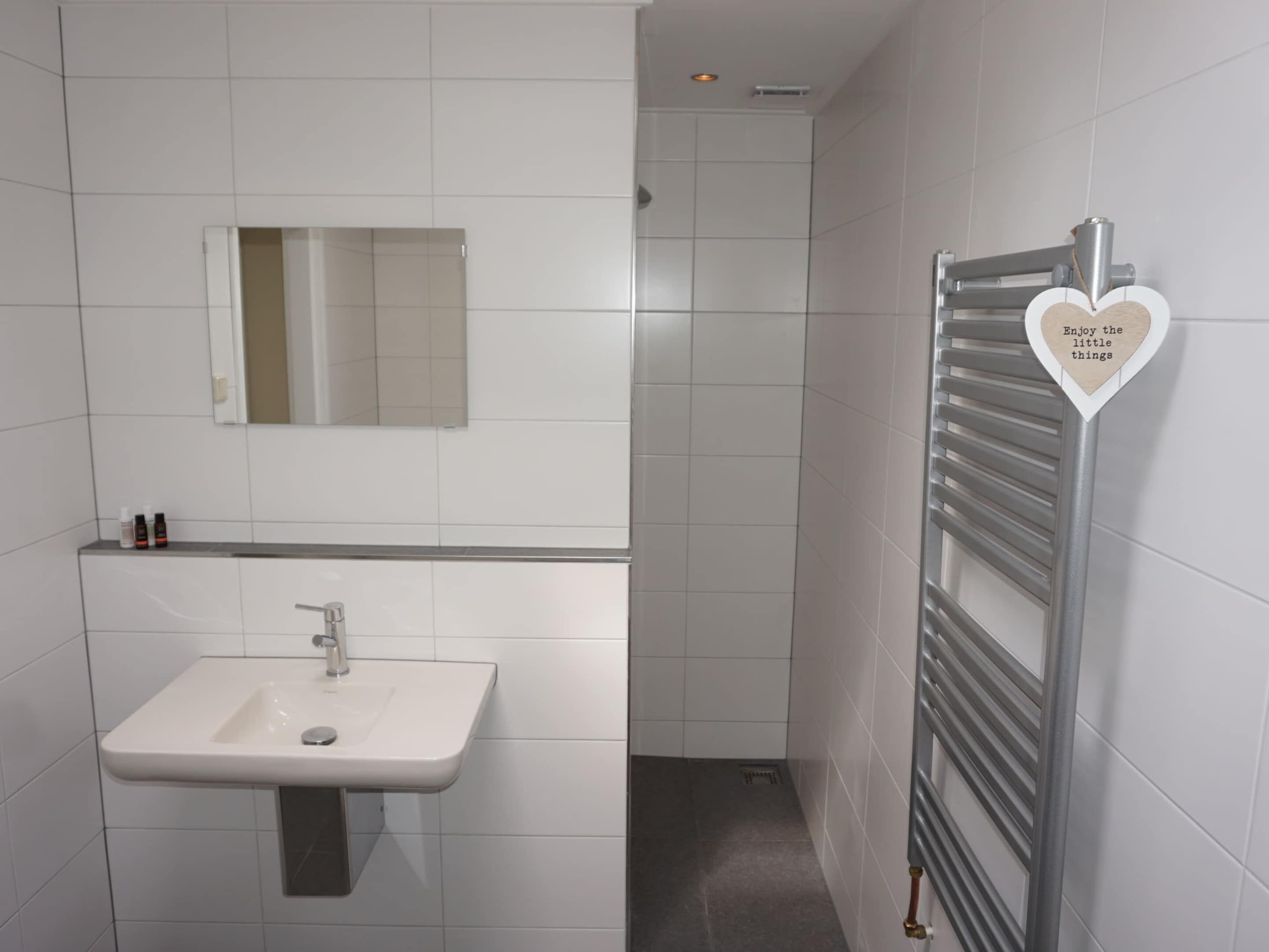 A modern bathroom with a white sink, mirror, and towel rack.