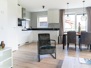 A modern kitchen with white cabinets, a black countertop, and a dining area with grey chairs and a table.