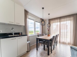 A modern kitchen with a sink, cabinets, and a dining area with a table and chairs.