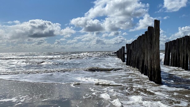A beach with waves, a wooden breakwater, and a partly cloudy sky. - Vacation Home Zeeland by Oosterschelde Park (Scherpenisse)
