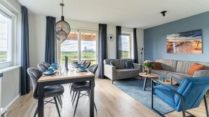 A modern living room with a dining area, a sofa, and a coffee table. - Modern Holiday Home by the sea With Sauna (Scherpenisse)