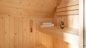 A wooden sauna room with a bottle of champagne, towels, and a sauna thermometer. - Modern Holiday Home by the sea With Sauna (Scherpenisse)