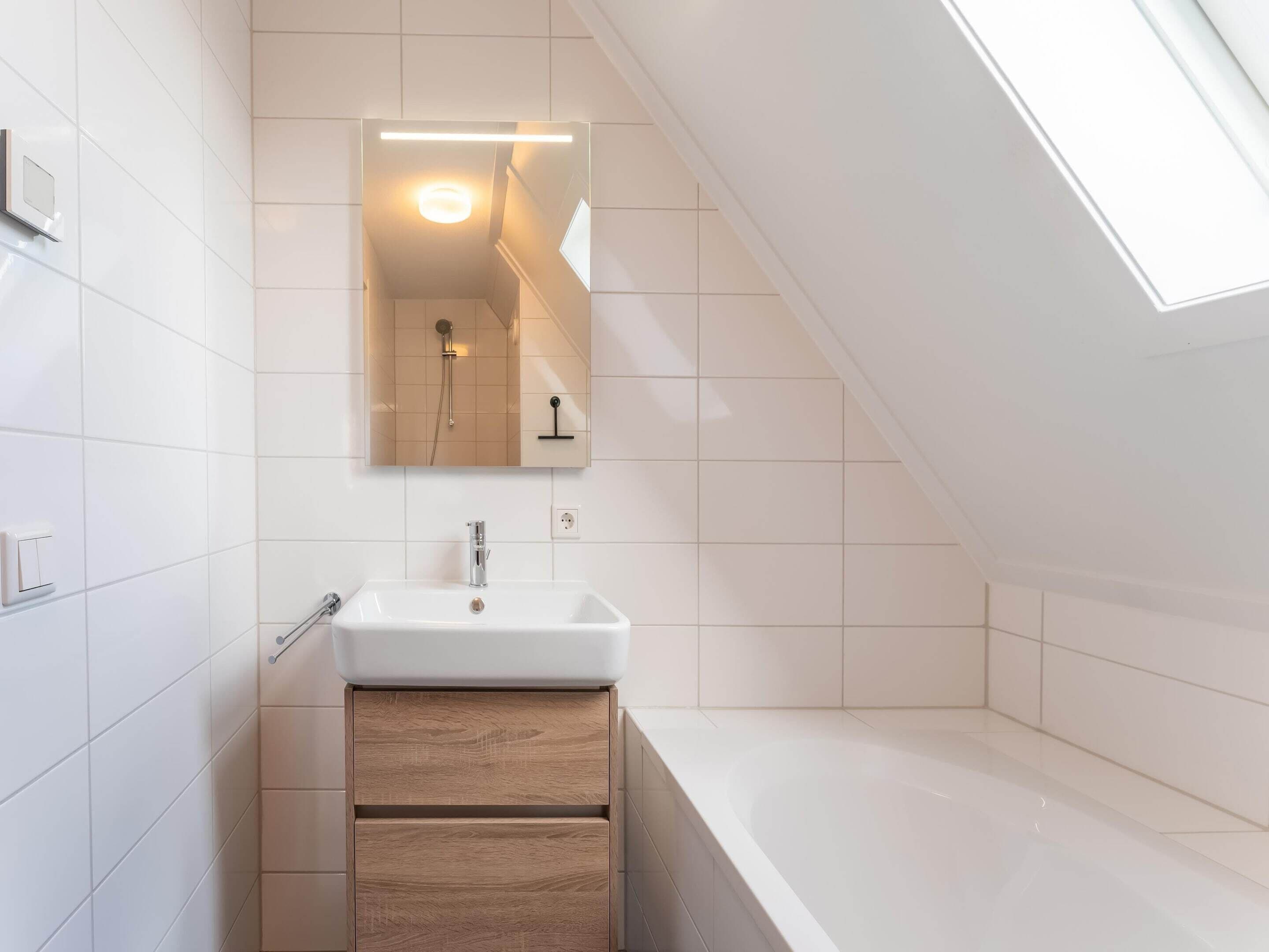 Un bagno moderno con un lucernario, un lavandino bianco e un mobile in legno.