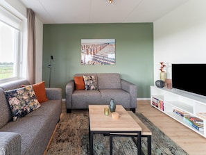 Un salon avec un canapé, une table basse, une bibliothèque et un tableau accroché au mur.