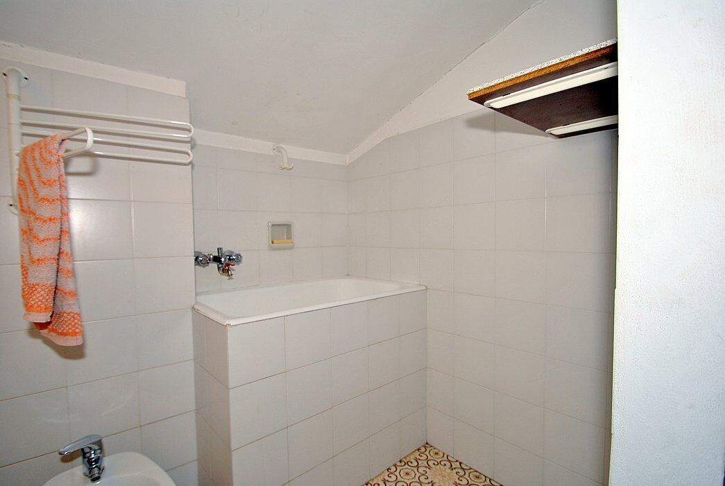 Een badkamer met een bad, een toilet en een handdoekrek met een oranje handdoek.