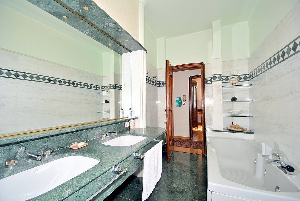 A bathroom with two sinks, a large mirror, and a bathtub.