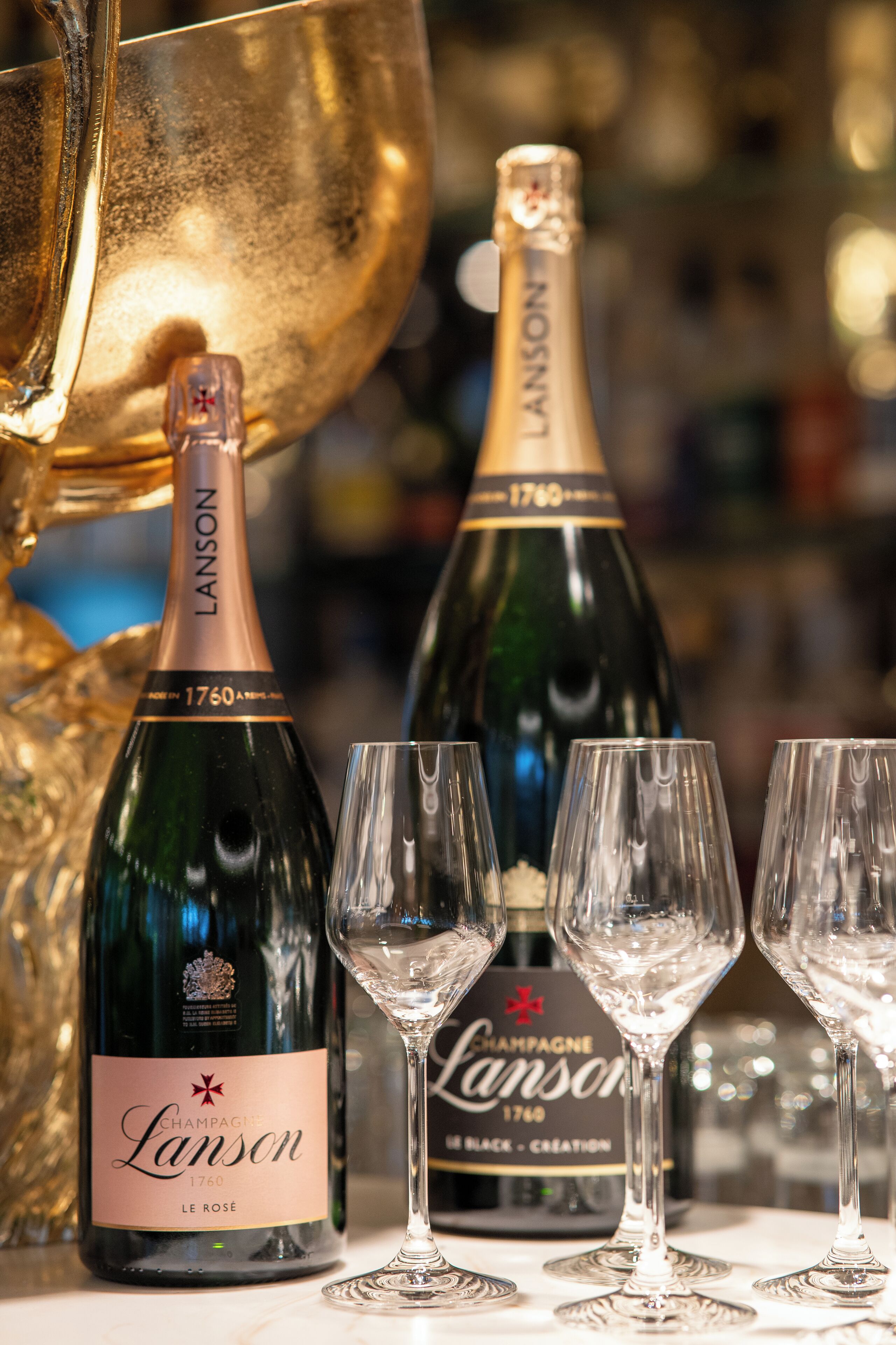 Two bottles of champagne and three glasses on a table.