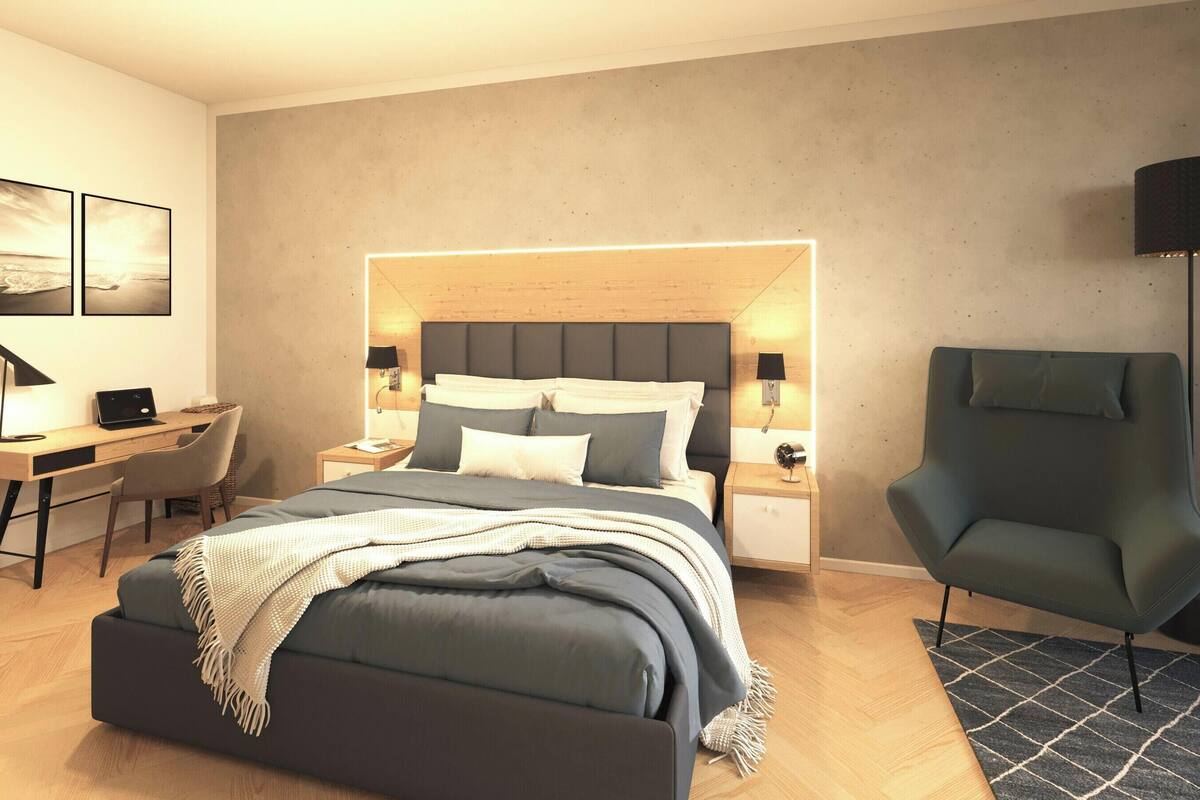 A modern bedroom with a bed, bedside tables, a desk, a chair, and a lamp.