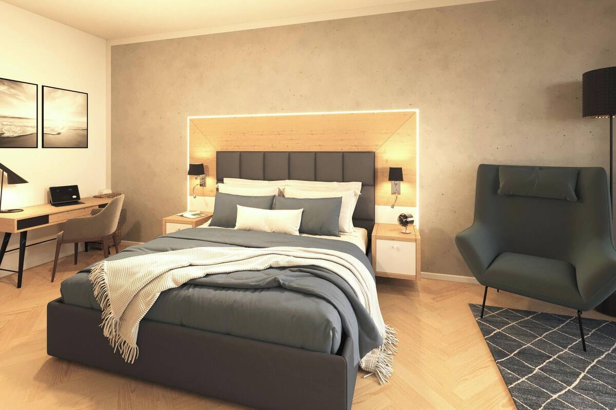A modern bedroom with a bed, bedside tables, a desk, a chair, and a lamp.