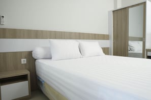 Una cama bien hecha con sábanas blancas en una habitación de hotel.