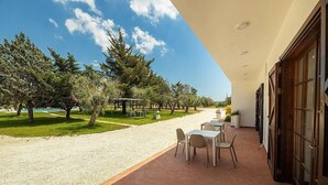 Eine Außenpatio-Terrasse mit Tischen und Stühlen, umgeben von Bäumen und einem Kiesweg.