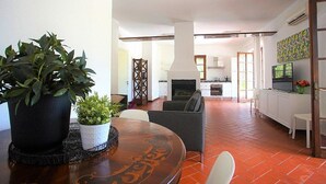 Ein modernes Wohnzimmer mit Esstisch, einer Couch und einer Küche im Hintergrund.