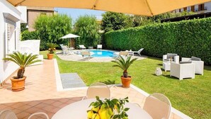 Ein Garten mit Schwimmbad, Sitzgelegenheiten im Freien und Blumentöpfen.
