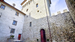 Ein Innenhof mit einem Steinhaus, das eine rote Tür und Rundbogenfenster zeigt.
