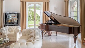 Un piano à queue, un canapé blanc et un coin bar avec des bouteilles.