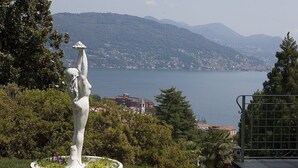 Une statue dans un jardin, avec vue sur un lac et des montagnes.