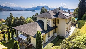Une maison à deux étages dotée d’un balcon, d’une piscine et offrant une vue sur un lac et des montagnes.