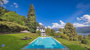 Une piscine avec des chaises longues, une maison et un paysage montagneux.