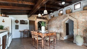 A rustic dining area with a stone fireplace, wooden furniture, and hanging light fixtures. - Villa Ignatia: A charming villa surrounded by vineyards and olive groves, with Free WI-FI. (Racale)