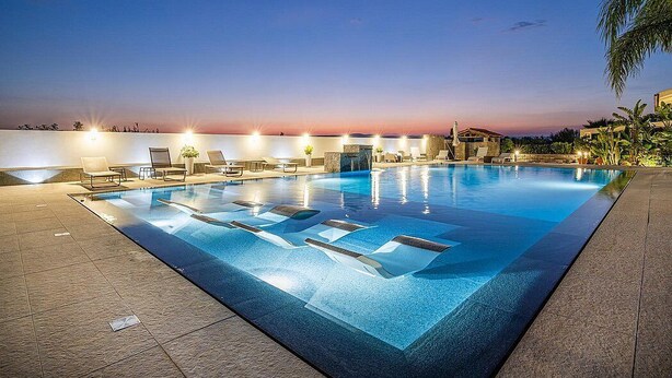 Ein Pool mit Liegestühlen und Blick auf den Sonnenuntergang.