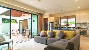 A modern living room with a grey sofa and a dining area with a table and chairs.